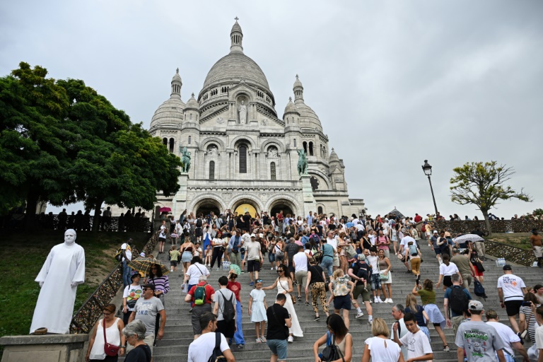 Des touristes montent vers la basilique du Sacré-Coeur à Montmartre, le 13 août 2025 à Paris