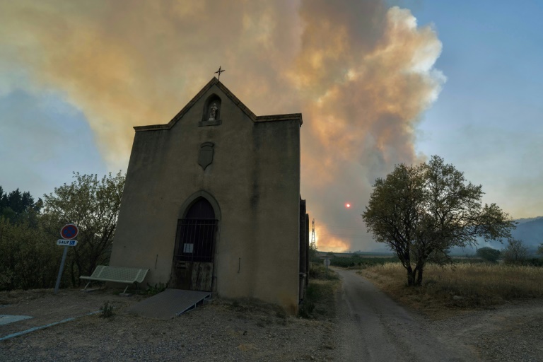 Les fumées d'un incendie visibles derrière une église à Tournissan, dans l'Aude, le 5 août 2025