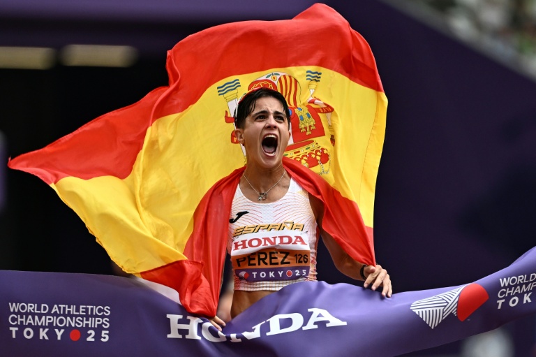 L'Espagnole Maria Perez tient le drapeau espagnol alors qu'elle franchit la ligne d'arrivée pour remporter la finale du 35 km marche féminin lors des Championnats du monde d'athlétisme, à Tokyo, le 13 septembre 2025