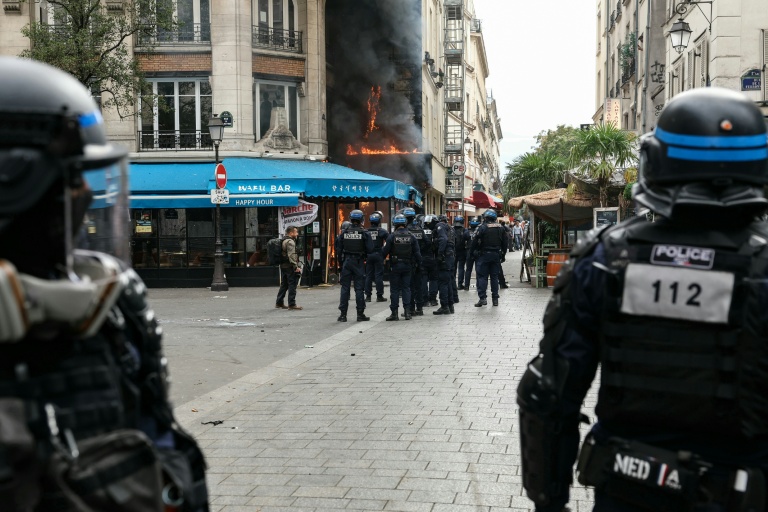Des policiers se tiennent à côté d'un restaurant en feu lors d'une manifestation à Paris, le 10 septembre 2025