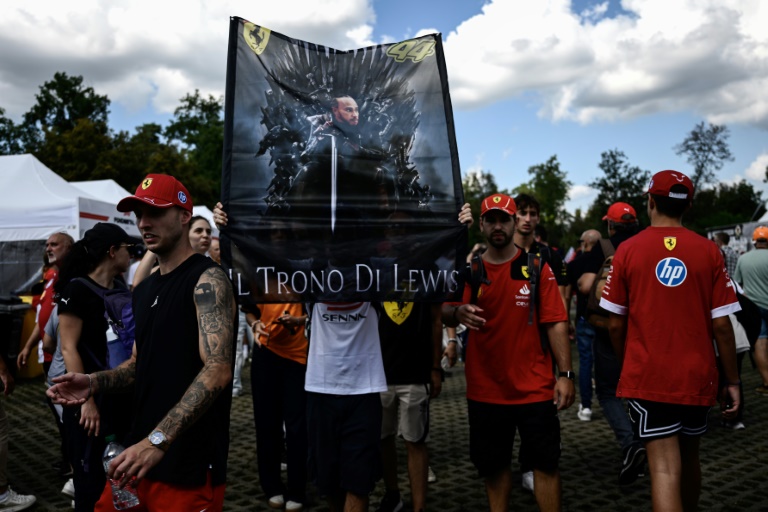 Des supporters du pilote britannique de Ferrari Lewis Hamilton arborent une affiche à son effigie lors du Grand Prix d'Italie de Formule 1 sur le circuit de Monza le 5 septembre 2025.