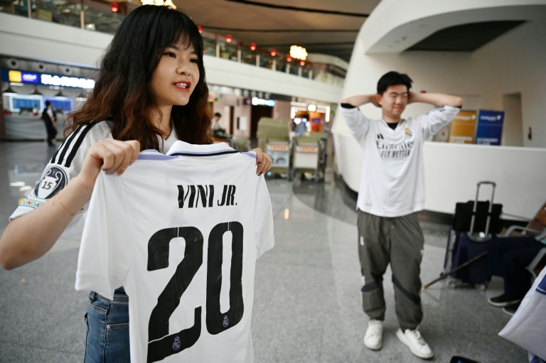 Rebecca Feng, une supportrice chinoise du Real Madrid, pose avec un maillot de Vinicius Jr à l'aéroport de Pékin, avant d'aller assister au match de Ligue des champions entre le Kaïrat Almaty et le Real Madrid le 29 septembre 2025