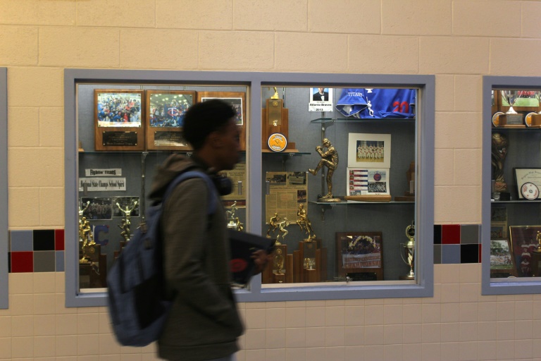 Un élève qui marche dans les couloirs du lycée public d'Alexandria, devant les trophées qu'a remportés Noah Lyles en étant adolescent, le 25 août 2025