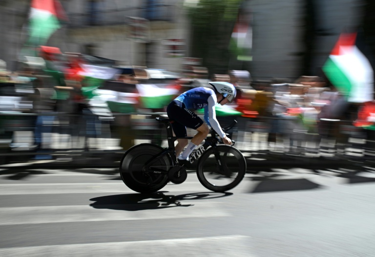 Des manifestants brandissent des drapeaux palestiniens lors du passage du cycliste britannique Jake Stewart de l'équipe Israel Premier Tech, lors du contre-la-montre individuel marquant la 18e étape du Tour d'Espagne, le 11 septembre 2025 à Valladolid