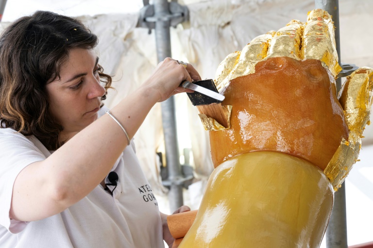 La restauratrice d'art Cyrielle D'Antoni travaille avec des feuilles d'or sur la statue de Jésus, à côté de la Vierge Marie, lors de la rénovation de la basilique Notre-Dame de la Garde à Marseille, le 3 septembre 2025