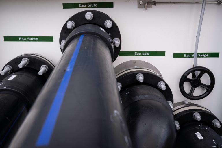Des conduites d'eau pour l'eau filtrée, l'eau brute, l'eau sale et l'eau de nettoyage sortent d'une unité mobile de traitement de la pollution de l'eau par les PFAS à Bartenheim, le 4 septembre 2025 dans le Haut-Rhin