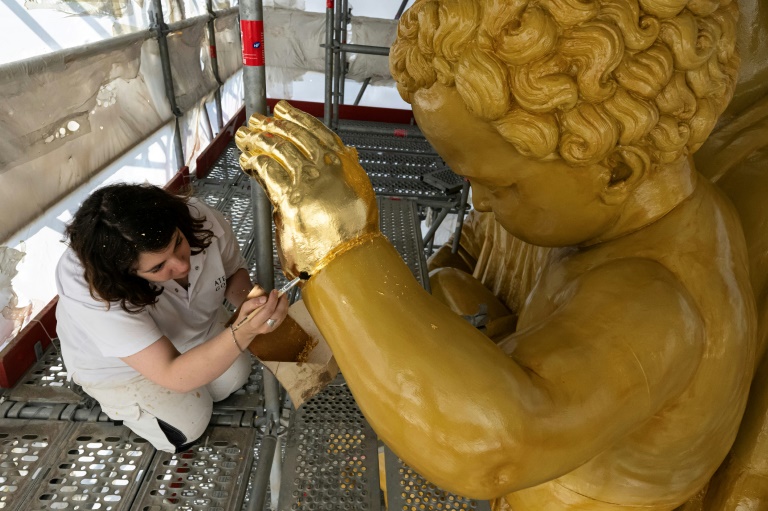 La restauratrice d'art Cyrielle D'Antoni travaille avec des feuilles d'or sur la statue de Jésus, à côté de la Vierge Marie, lors de la rénovation de la basilique Notre-Dame de la Garde à Marseille, le 3 septembre 2025