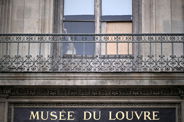 Une personne derrière la fenêtre par laquelle sont entrés les voleurs au musée du Louvre la veille, à Paris, le 20 octobre 2025