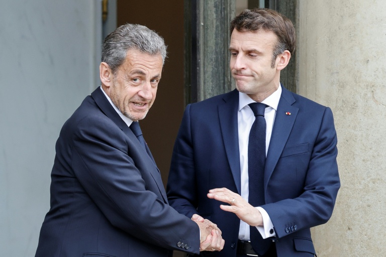 Le président Emmanuel Macron (d.) serre la main de l'ancien chef de l'Etat Nicolas Sarkozy après une réunion au palais de l'Elysée, à Paris, le 25 février 2022