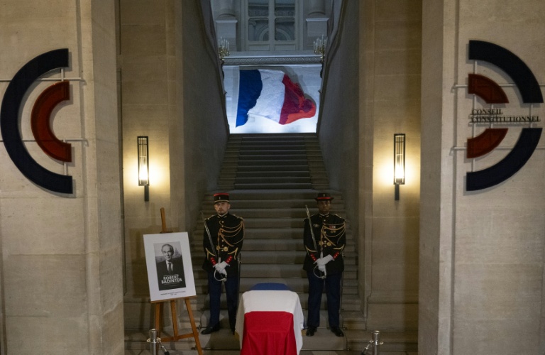 Des gardes républicains montent la garde près du portrait de feu Robert Badinter et d'un cercueil recouvert d'un drapeau français lors d'une veillée funèbre au Conseil constitutionnel à Paris, le 8 octobre 2025
