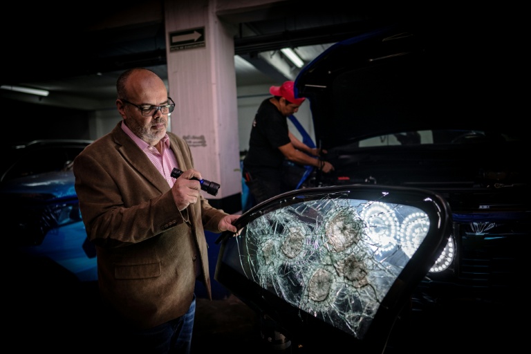 Leopoldo Cerdeira, directeur d'une entreprise de sécurité, montre l'efficacité de ses vitres de protection, criblées de balle, le 3 octobre 2025 à Mexico