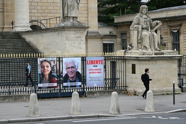 Des portraits de Cécile Kohler et de Jacques Paris, détenus en Iran, installés sur une grille de l'Assemblée nationale à Paris, le 6 octobre 2025