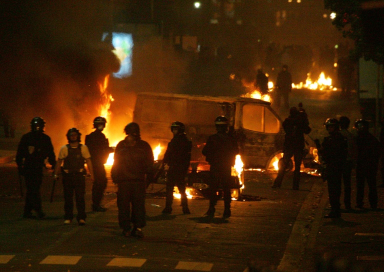 Des policiers devant des véhicules incendiés, le 28 octobre 2005 à Clichy-sous-Bois, en Seine-Saint-Denis, où de nouvelles violences urbaines ont éclaté entre des jeunes des quartiers difficiles et les forces de l'ordre