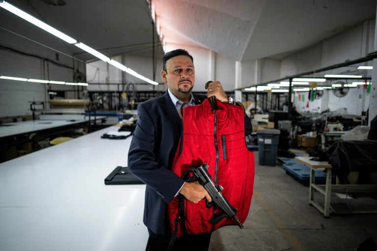 Gabriel Hernandez, directeur d'une entreprise de sécurité, pose dans les locaux de sa société avec un gilet pare-balles et un fusil, le 6 octobre 2025 à Mexico