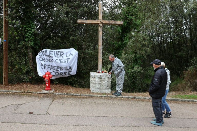 Une banderole à côté d'une croix en bois objet de polémiques à l'entrée du village de Quasquara, le 14 octobre 2025 en Corse-du-Sud