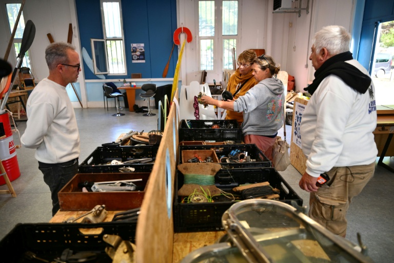 Thomas Bekkers (G) et Oscar Damaso (D) discutent avec des clients dans la ressourcerie de la Tribu maritime, le 7 novembre 2025 à Port-Saint-Louis-du-Rhône, dans les Bouches-du-Rhône