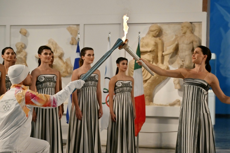 L'actrice grecque Mary Mina transmet la flamme olympique au premier relayeur pour les Jeux d'hiver 2026 de Milan-Cortina, le Grec Petros Gaidatzis, lors d'une cérémonie au Musée antique d'Olympie, en Grèce, le 26 novembre 2025