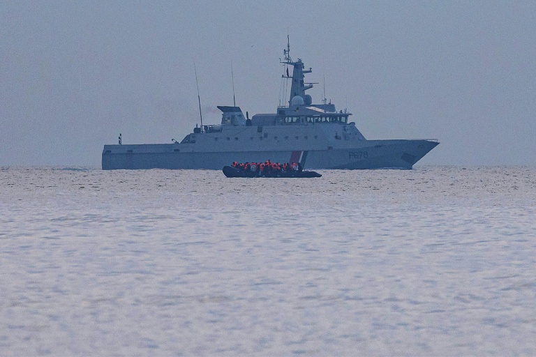 Un taxi-boat, transportant des migrants qui veulent traverser la Manche, passe devant un navire militaire français au large de la plage de Gravelines, dans le nord de la France, le 12 août 2025