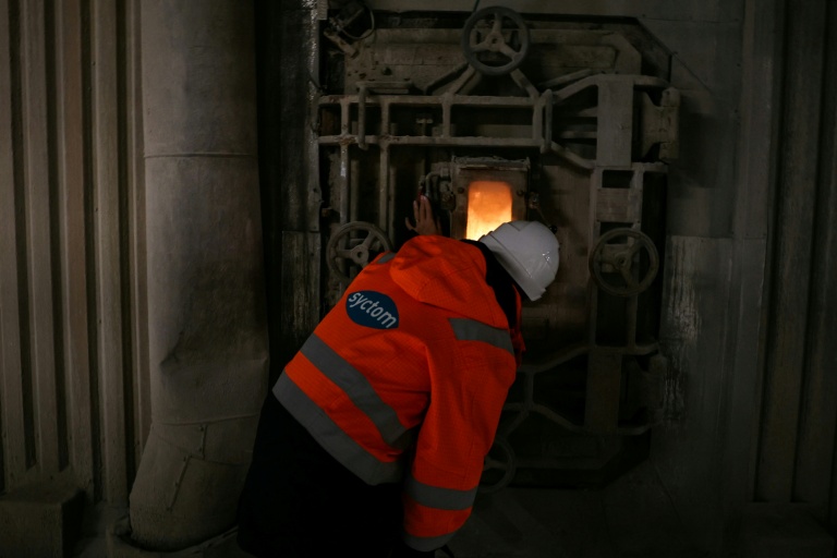 Un employé observe par une fenêtre les déchets qui brûlent dans un four de l'incinérateur Isséane Syctom d'Issy-les-Moulineaux, le 25 novembre 2025 en périphérie de Paris