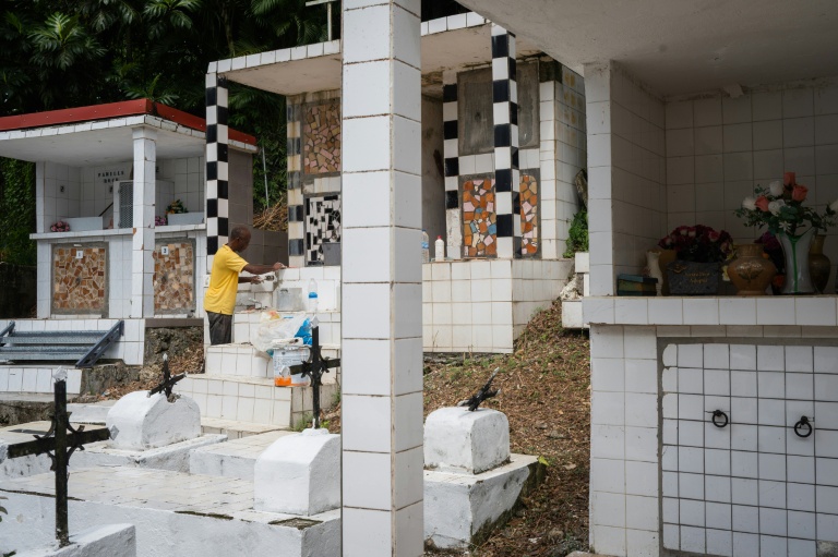 Un membre de la famille Vainqueur décore une tombe dans le cimetière privé de la famille aux  Abymes, en Guadeloupe, le 31 octobre 2025