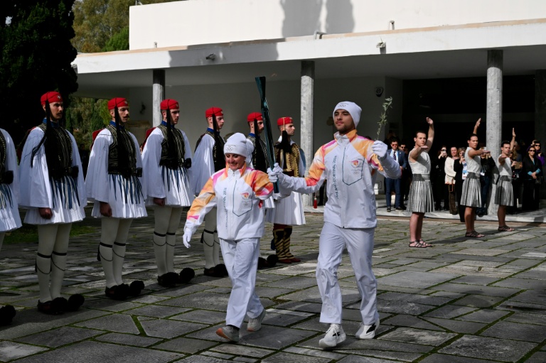 L'Italienne Stefania Belmondo et le Grec Petros Gaidatzis portent ensemble la flamme olympique à la sortie du musée du site antique d'Olympie, en Grèce, le 26 novembre 2025