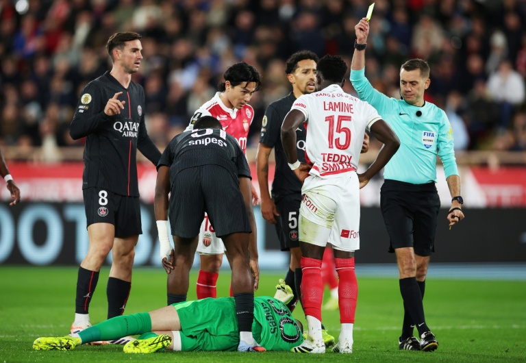 L'arbitre Clément Turpin sanctionne d'un carton jaune le milieu de Monaco Lamine Camara (2e en partant de la droite) pour une faute sur le gardien parisen Lucas Chevalier (au sol), le 29 novembre 2025 à Monaco