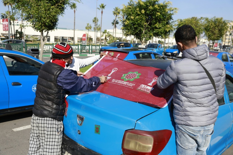 Des personnes décorent des taxis avec le logo de la Coupe d'Afrique des nations (CAN) 2025 à Rabat, au Maroc, le 14 décembre 2025