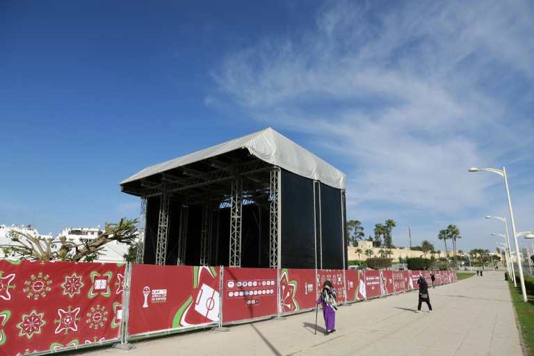 Des passants marchent devant une fan zone de la Coupe d'Afrique des nations (CAN) 2025, l'une de celles prévues par la CAF, à Salé, au Maroc, le 14 décembre 2025