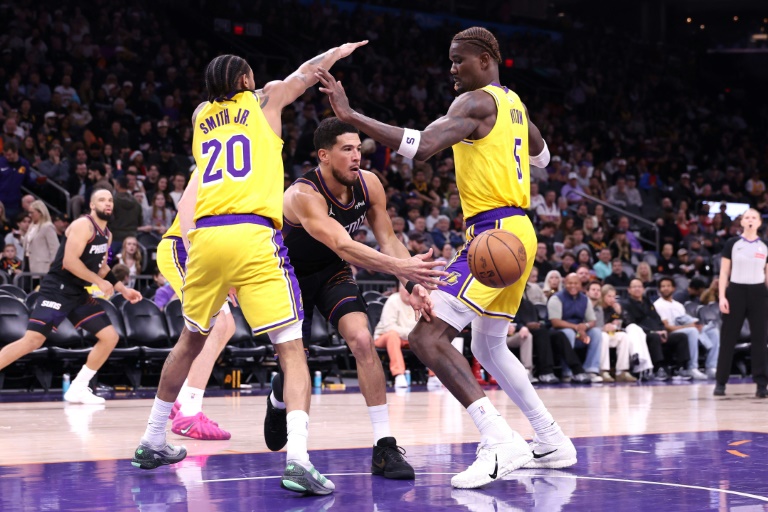 Devin Booker donne une passe entre Nick Smith Jr. (à gauche) and Deandre Ayton (à droite) lors d'une victoire des Phoenix Suns contre les Los Angeles Lakers, le 24 décembre 2025 à Phoenix
