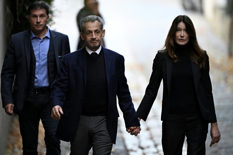 Nicolas Sarkozy (C) et son épouse Carla Bruni-Sarkozy, le jour de son incarcération à la prison de la Santé, le 21 octobre 2025 à Paris