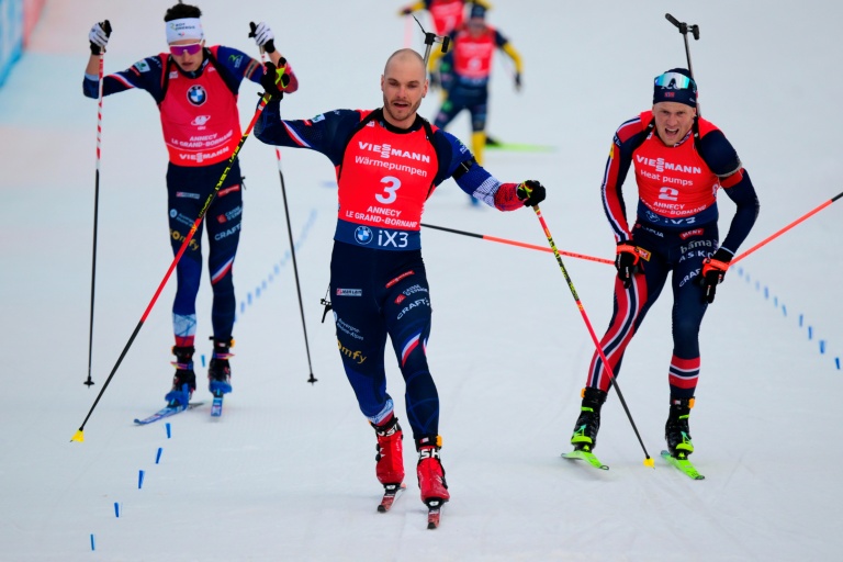 Les biathlètes français Eric Perrot (à gauche), Emilien Jacquelin (au centre) et norvégien Johannes Dale-Skjevdal (à droite) franchissent la ligne d'arrivée de l'épreuve de la poursuite masculine 12,5 km au Grand Bornand (France) le 20 décembre 2025.