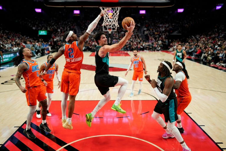 Deni Avdija (c.), l'ailier israélein des Portland Trail Blazers, marque un panier devant Shai Gilgeous-Alexander (g.), le meneur du Thunder d'Oklahoma City, lors d'une rencontre de NBA à Portland, le 30 novembre 2025