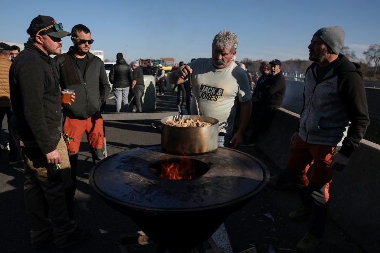 Des agriculteurs préparent un repas lors du blocage d'une portion de l'autoroute A64 à Carbonne, dans le sud-ouest, le 13 décembre 2025