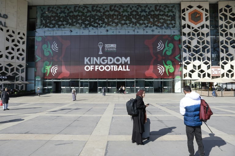 Des passants déambulent près de la gare ferroviaire Rabat-Agdal décorée aux couleurs de la Coupe d'Afrique des nations (CAN) 2025 à Rabat, au Maroc, le 14 décembre 2025