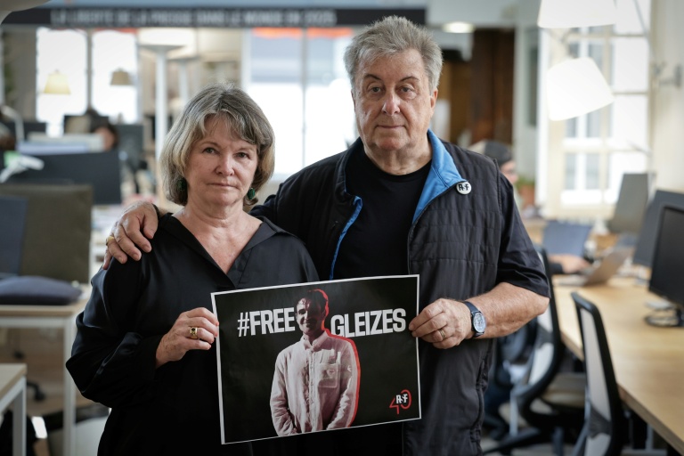 La mère du journaliste Christophe Gleizes, Sylvie Godard, et son beau-père Francis Godard posent avec une affiche demandant sa libération, le 27 août 2025 à Paris