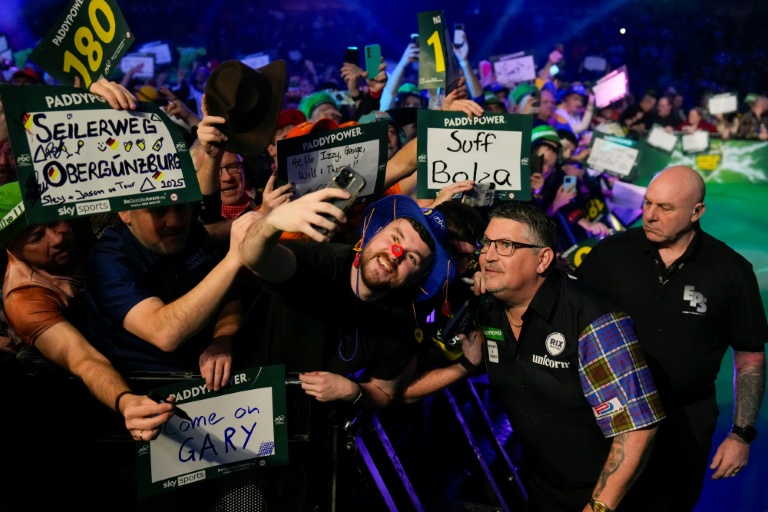 Le joueur de fléchette écossais Gary Anderson (2e à partir de la droite) prend la pause avec des supporters aux Mondiaux de fléchettes, à Londres le 28 décembre 2025