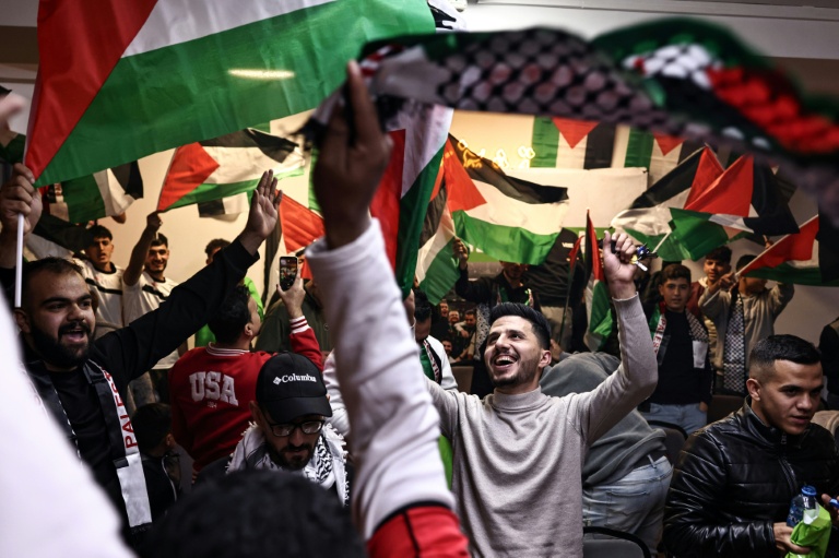 Des Palestiniens expriment leur joie le 7 décembre 2025 dans un café de Ramallah, en Cisjordanie occupée, après la qualifiation historique de leur équipe pour les quarts de finale de la Coupe arabe