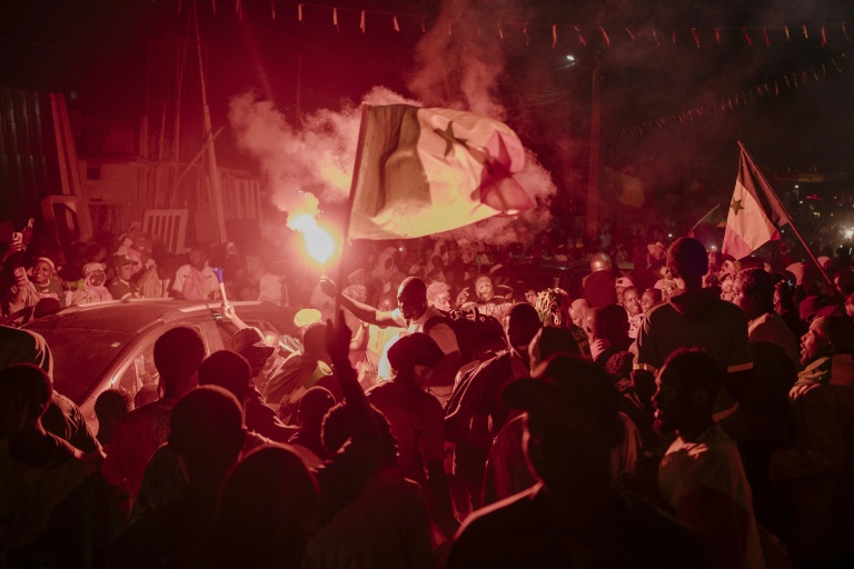 Des supporters sénégalais brandissent le 18 janvier 2026 à Dakar un drapeau du pays en célébrant la victoire de l'équipe de football sénégalaise face au Maroc en finale de  CAN-2025, le 18 janvier 2026 à Dakar