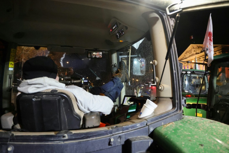 Un agriculteur dans son tracteur garé devant l'Assemblée nationale,  à Paris, le 13 janvier 2026