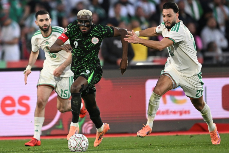 Le défenseur algérien Rayan Ait-Nouri (G) aux prises avec le Nigérian Victor Osimhen (C) cerné par l'autre défenseur algérien Ramy Bensebaini (D) lors de la victoire du Nigeria 2-0 en quart de finale de la CAN-2025, le 10 janvier 2026 à Marrakech