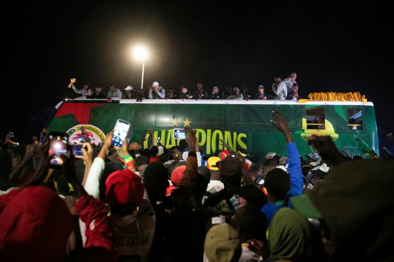 Des supporters de l'équipe de football du Sénégal accueillent le 20 janvier 2026 le bus des joueurs de retour du Maroc, après leur victoire en finale de la CAN-2025 face au Maroc