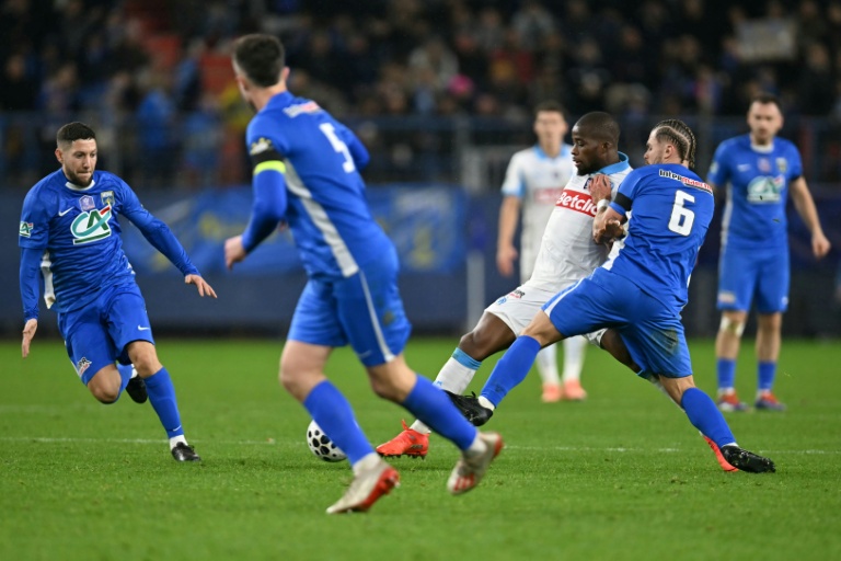 Le joueur de Marseille Hamed Traoré aux prises avec des joueurs de Bayeux, lors d'un match de Coupe de France, à Caen, le 13 janvier 2026