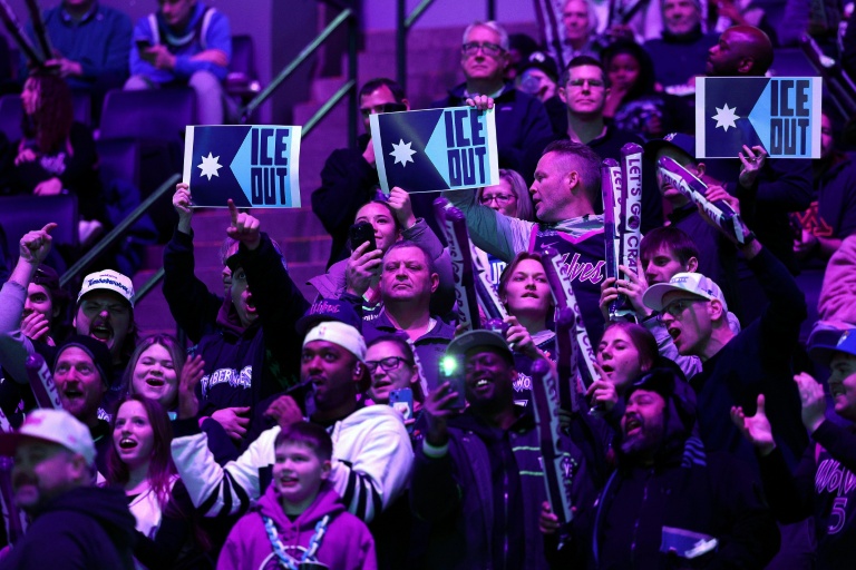 Des spectateurs brandissent des pancartes pour protester contre la présence d'agents fédéraux de l'immigration à Minneapolis, lors du match de NBA entre les Minnesota Timberwolves et les Golden State Warrior, à Minneapolis, le 25 janvier 2026