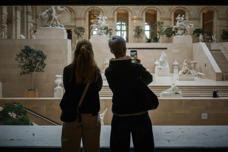 Des touristes observent l'intérieur du musée du Louvre, fermé lors d'une grève du personnel, le 15 décembre 2025 à Paris