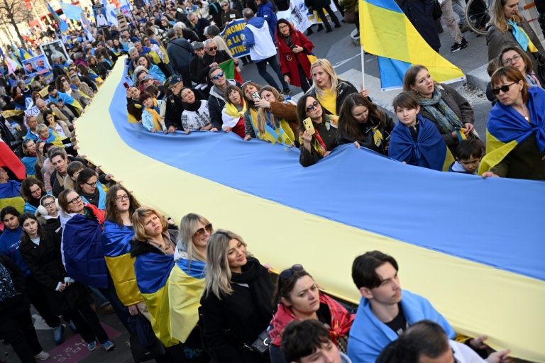Des manifestants brandissent un drapeau ukrainien géant lors d'une marche pour l'Ukraine à Paris, à l'approche du quatrième anniversaire de l'invasion russe, le 21 février 2026