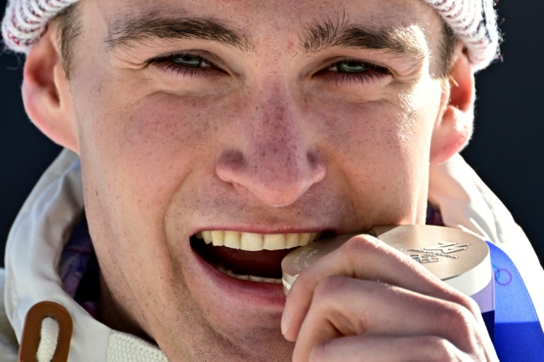Le fondeur français Mathis Desloges mord sa médaille d'argent lors des JO-2026, à Lago di Tesero en Italie, le 8 février 2026