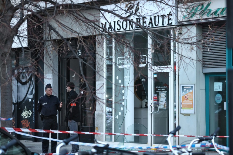 Des policiers devant la vitrine d'un salon de beauté contre lequel une grenade a été lancée à Grenoble, le 6 février 2026 en Isère