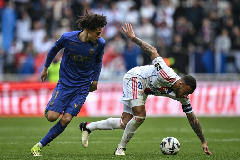 Corentin Tolisso, de Lyon, et Maghnes Akliouche (g), de Monaco, à la lutte pour le ballon en Ligue 1 le 22 mars 2022 au Groupama Stadium à Décines-Charpieu dans l'agglomération lyonnaise