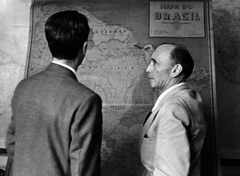 Dans les bureaux de l'Agence France Presse à Rio de Janeiro, Edgar Maufrais (D) et Chico Meirelles, pacificateur des Chavantes, discutent devant une carte du Brésil le parcours qu'il vient de réaliser à la recherche de son fils, l'explorateur Raymond Maufrais, disparu en janvier 1950