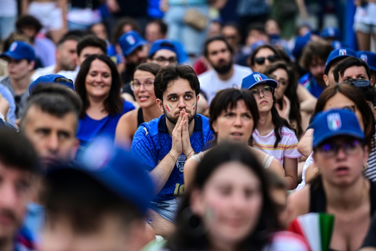Des supporters de l'Italie suivant sur un écran géant le huitième de finale de l'Euro-2024 perdu par la Nazionale face à la Suisse le 29 juin 2024 devant la gare centrale de Milan